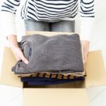 A shot of a woman boxing clothing items for storage.